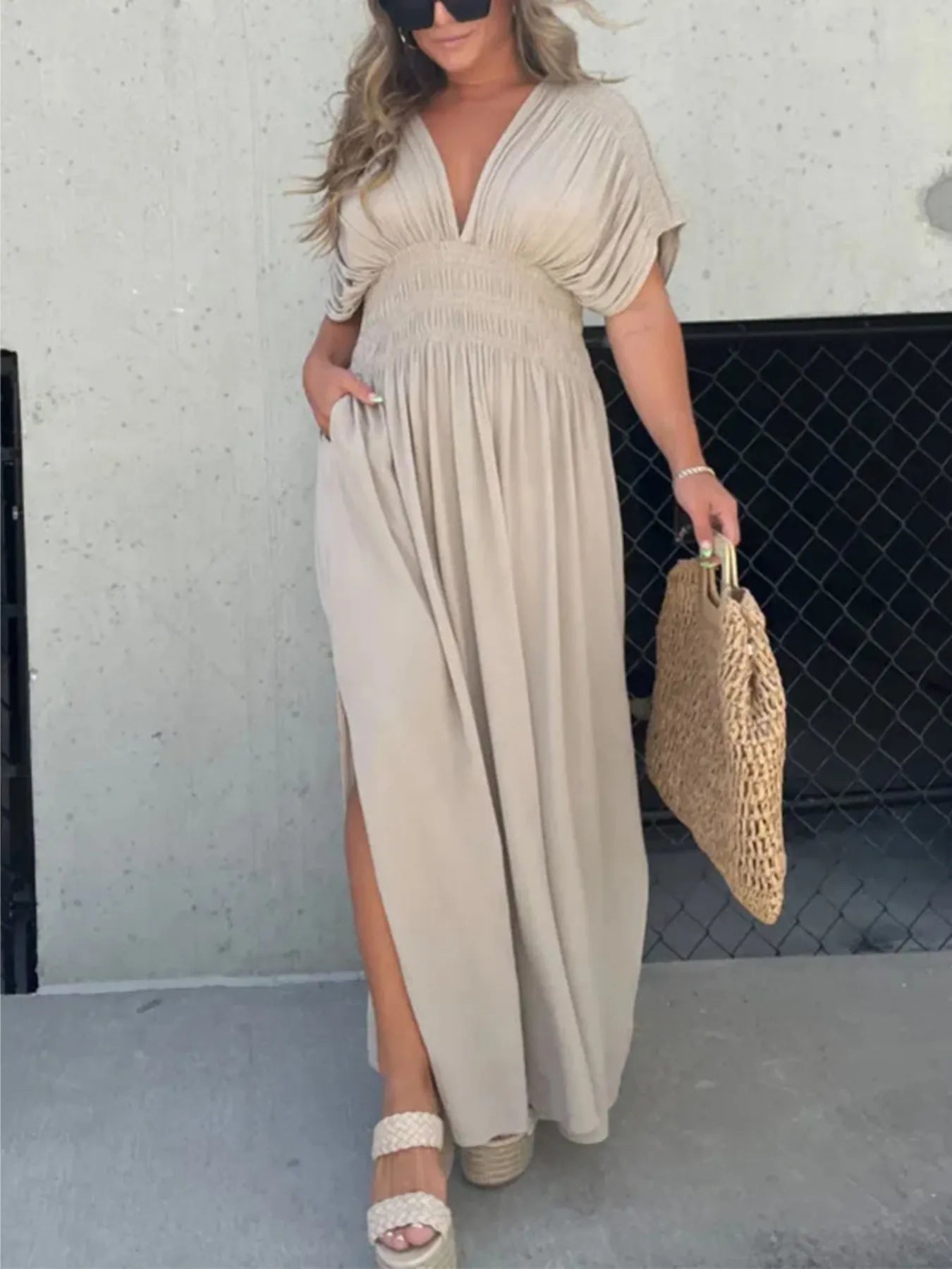 Woman wearing a flowing black deep V-neck maxi dress with side slit and relaxed elegant silhouette.