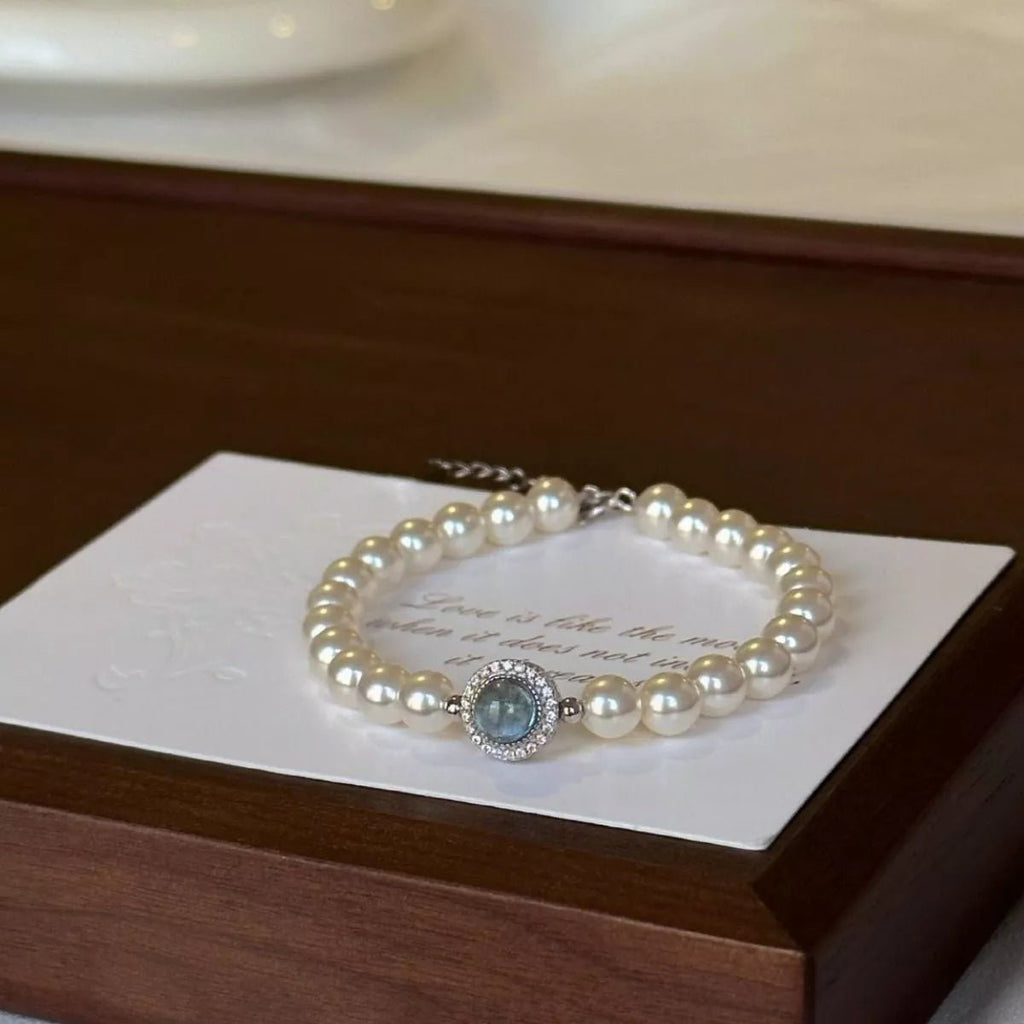Sterling silver pearl bracelet featuring a blue gemstone centerpiece and elegant beaded design.