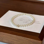 Gold floral pearl bracelet with delicate crystal accents and feminine detailing.