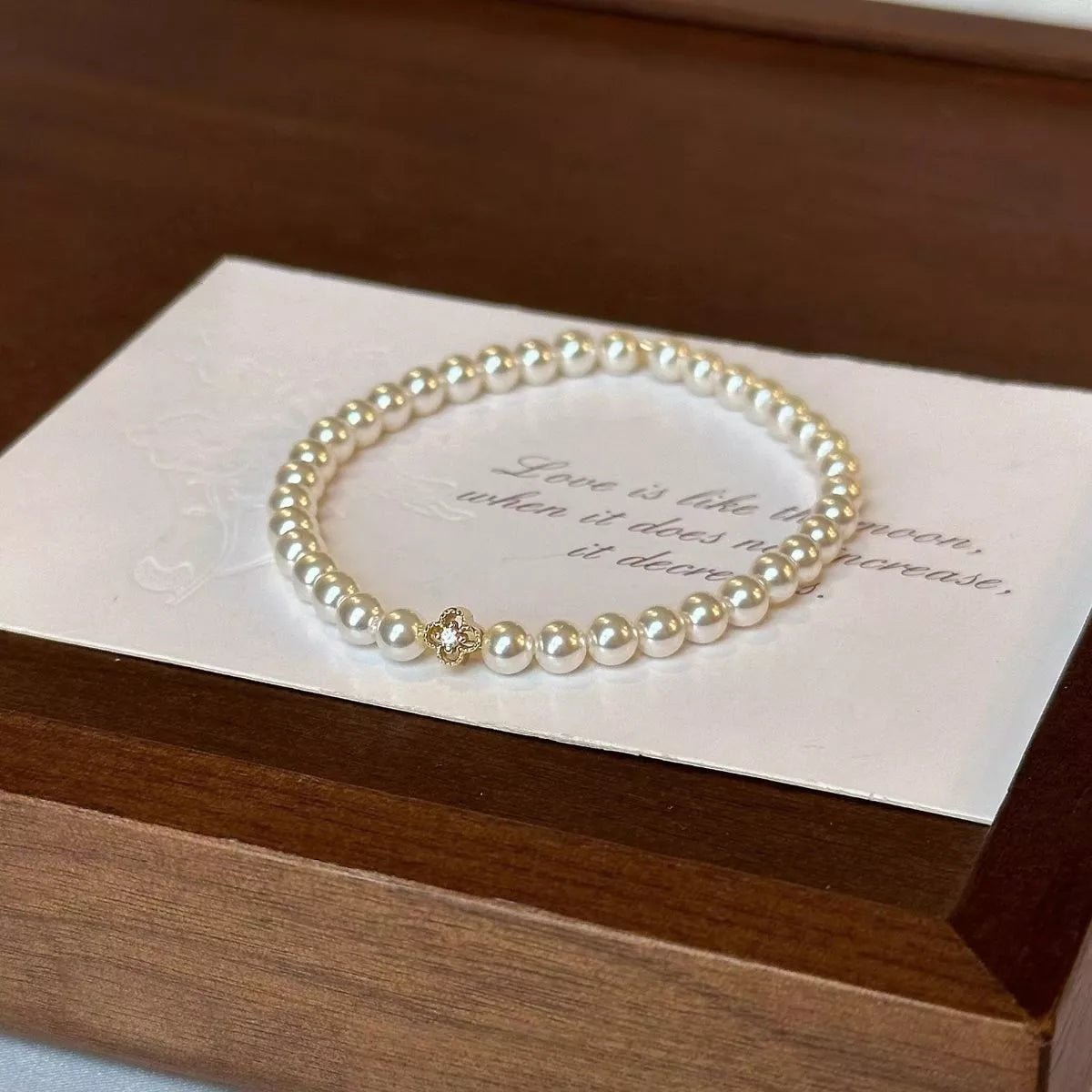 Gold floral pearl bracelet with delicate crystal accents and feminine detailing.