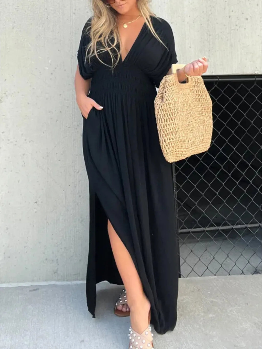 Woman wearing a flowing black deep V-neck maxi dress with side slit and relaxed elegant silhouette.