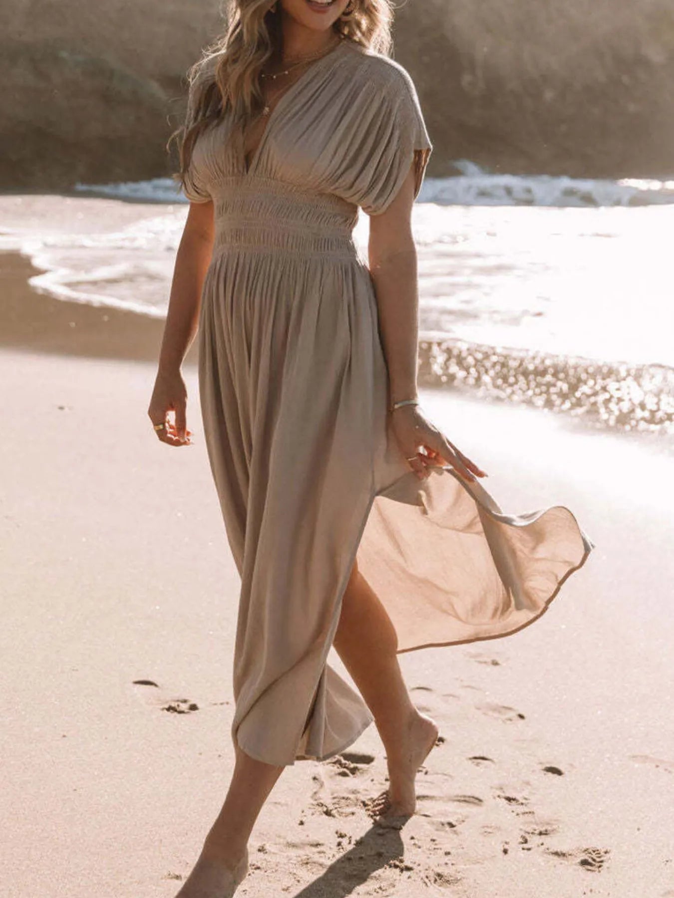 Woman wearing a flowing black deep V-neck maxi dress with side slit and relaxed elegant silhouette.