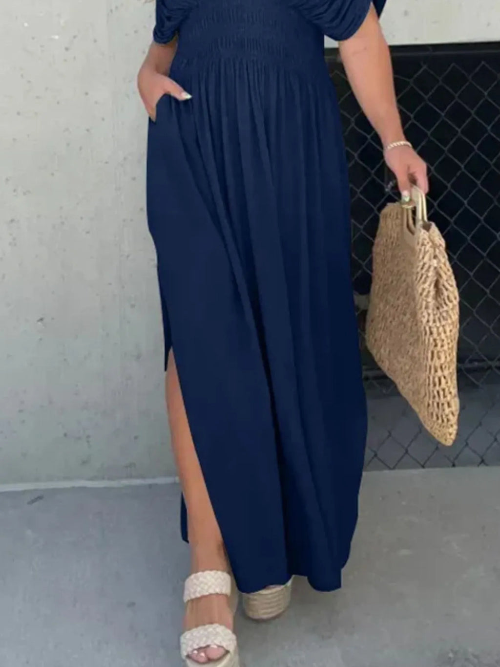 Woman wearing a flowing black deep V-neck maxi dress with side slit and relaxed elegant silhouette.