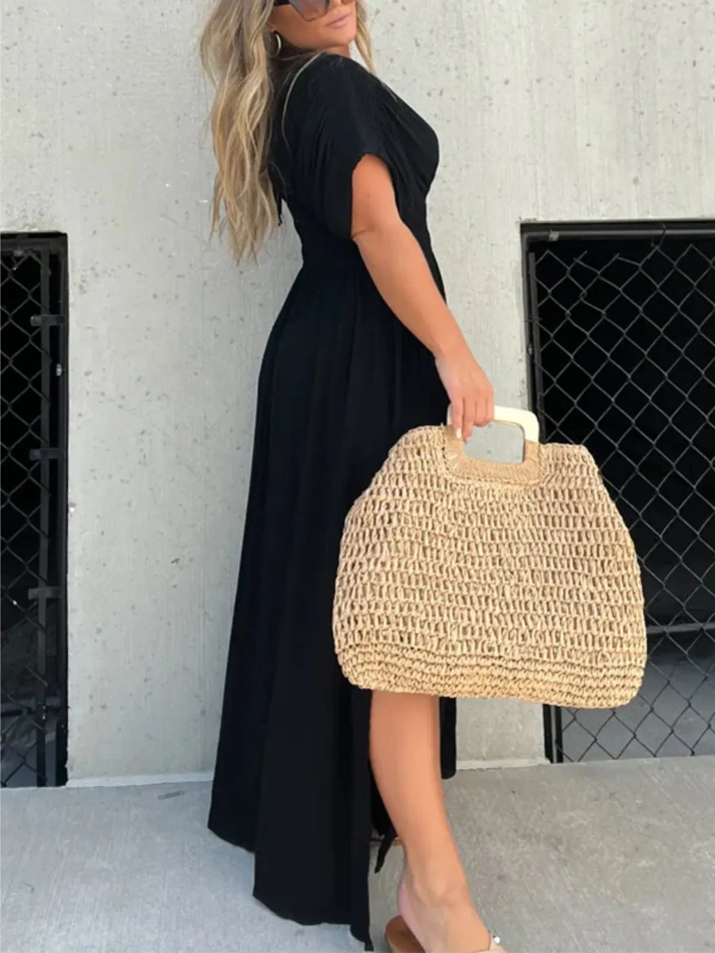 Woman wearing a flowing black deep V-neck maxi dress with side slit and relaxed elegant silhouette.