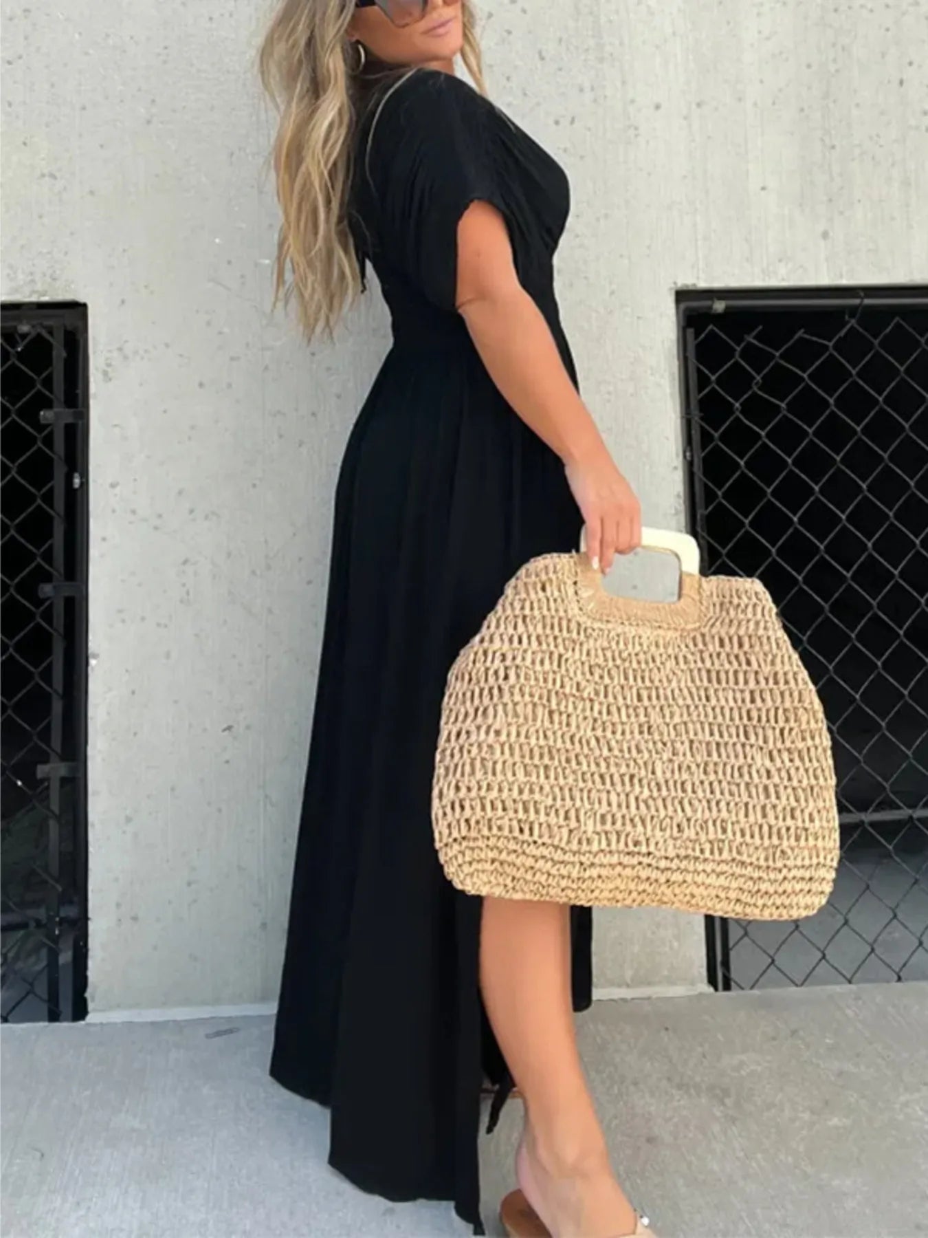 Woman wearing a flowing black deep V-neck maxi dress with side slit and relaxed elegant silhouette.