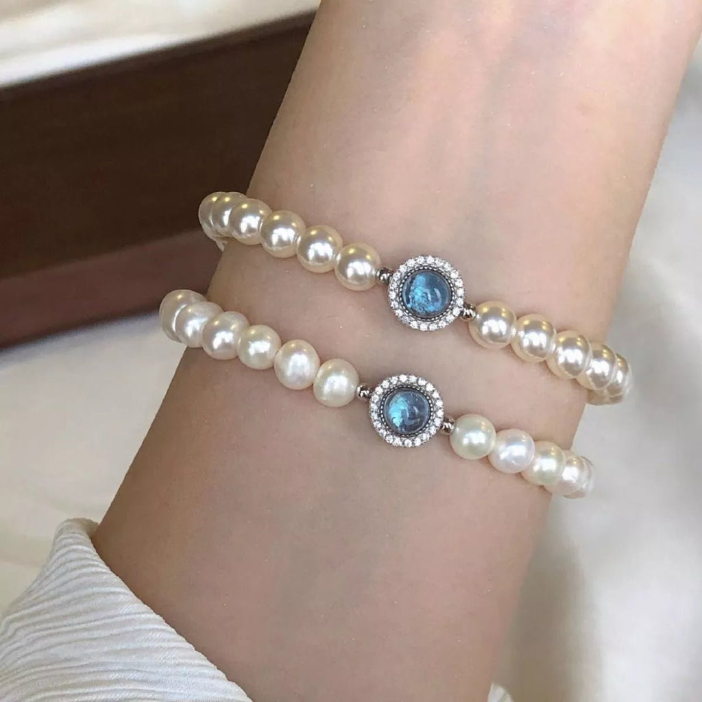 Sterling silver pearl bracelet featuring a blue gemstone centerpiece and elegant beaded design.
