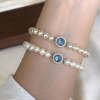 Sterling silver pearl bracelet featuring a blue gemstone centerpiece and elegant beaded design.