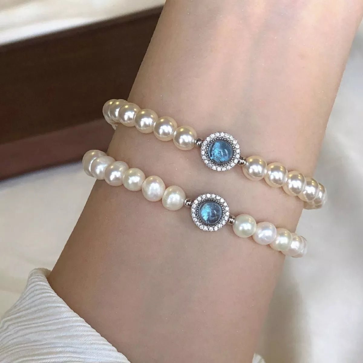 Sterling silver pearl bracelet featuring a blue gemstone centerpiece and elegant beaded design.