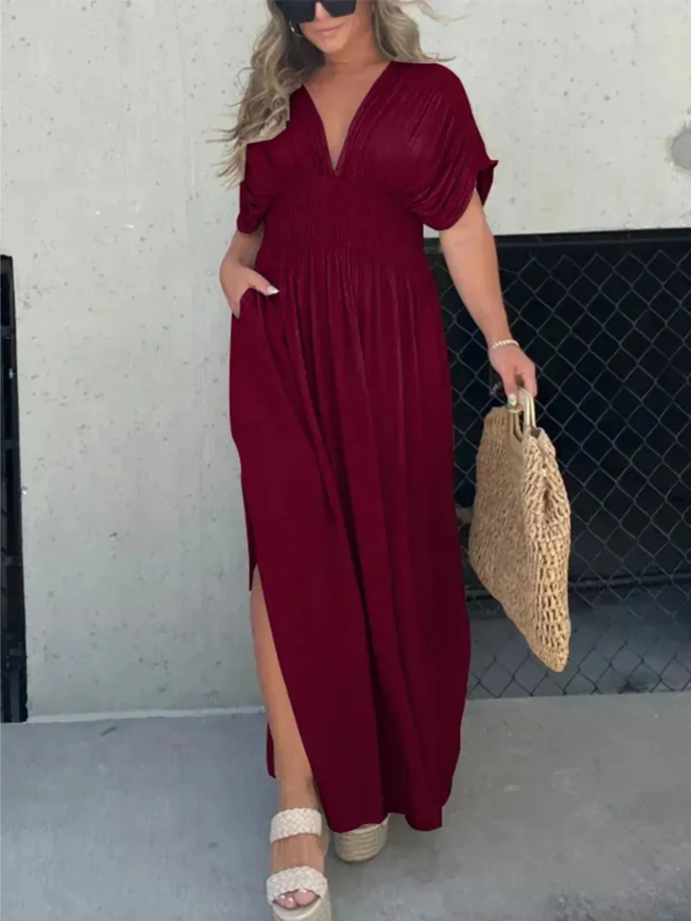 Woman wearing a flowing black deep V-neck maxi dress with side slit and relaxed elegant silhouette.