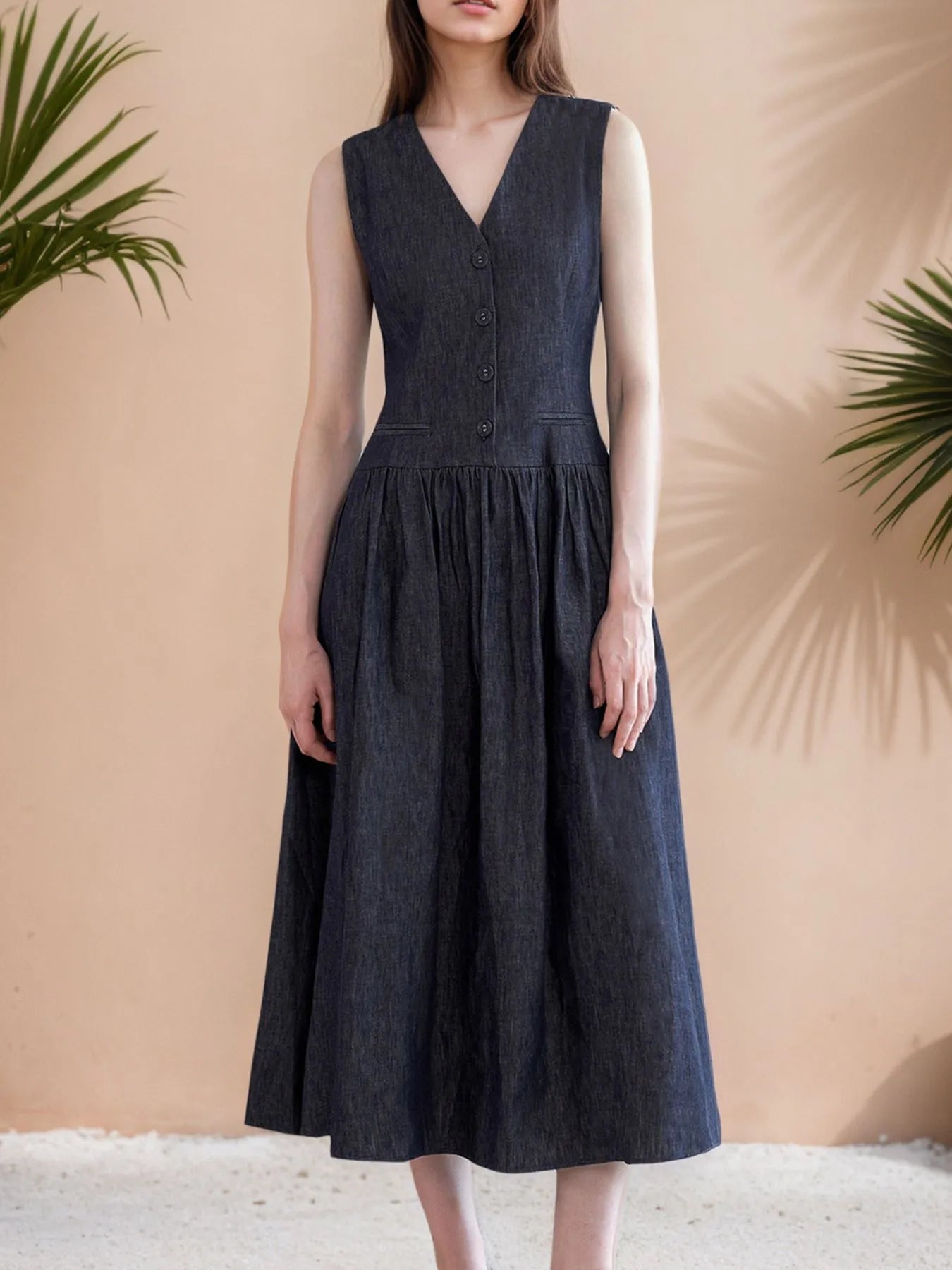 Elegant sleeveless navy midi dress with V-neckline and button-front detailing.