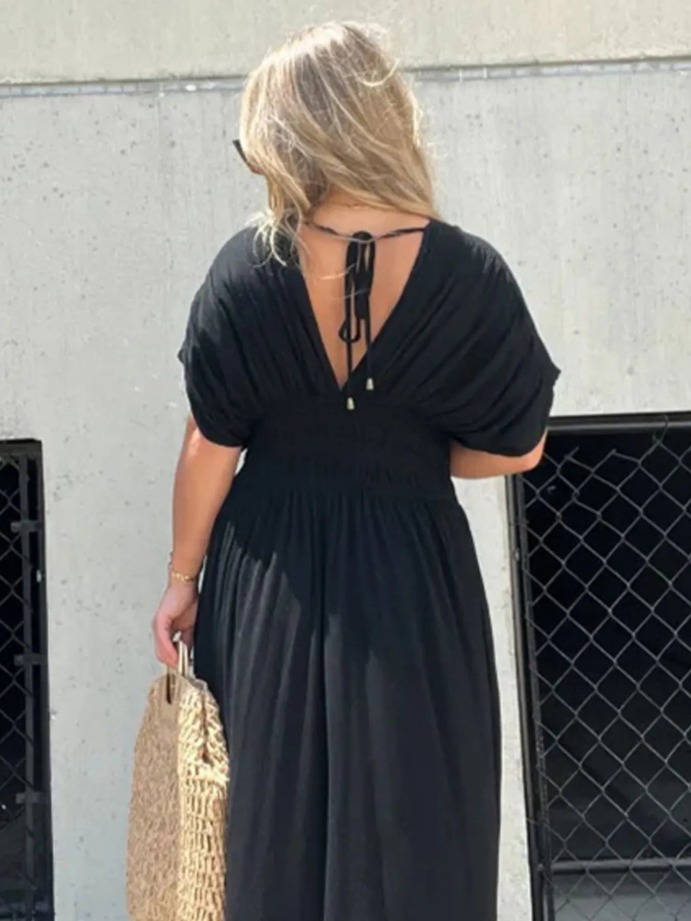 Woman wearing a flowing black deep V-neck maxi dress with side slit and relaxed elegant silhouette.