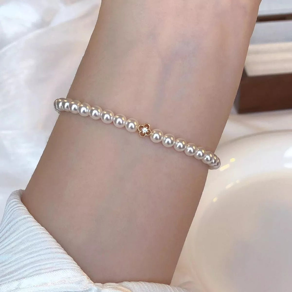 Gold floral pearl bracelet with delicate crystal accents and feminine detailing.