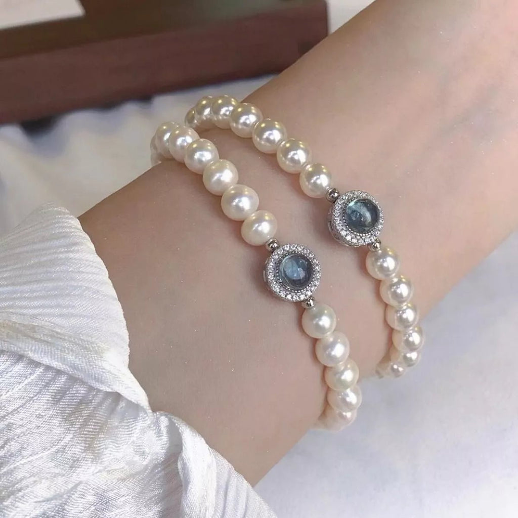 Sterling silver pearl bracelet featuring a blue gemstone centerpiece and elegant beaded design.