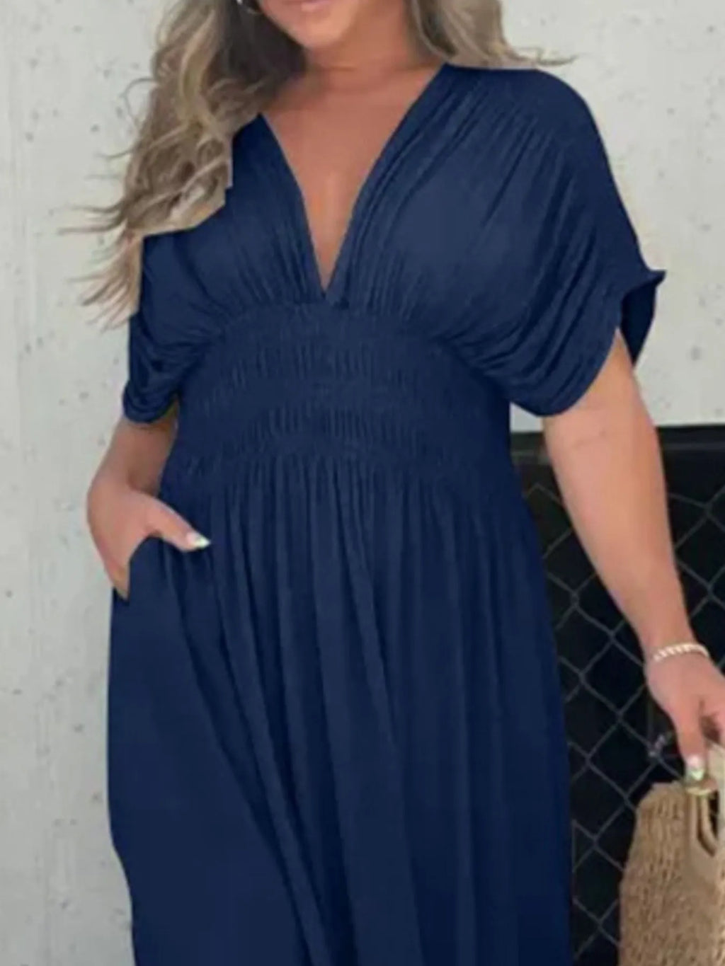 Woman wearing a flowing black deep V-neck maxi dress with side slit and relaxed elegant silhouette.