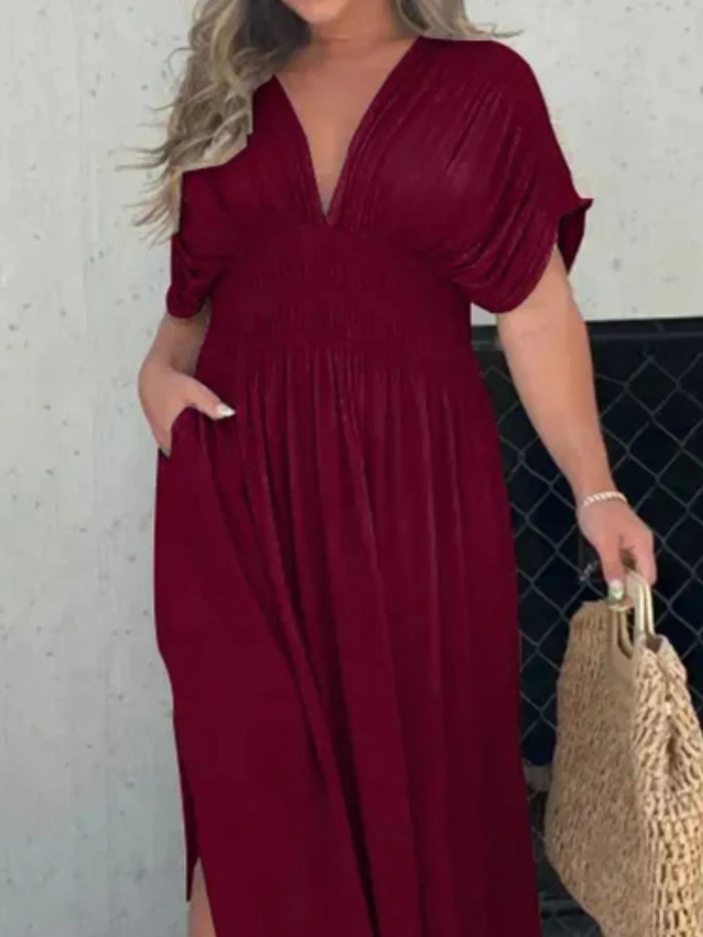 Woman wearing a flowing black deep V-neck maxi dress with side slit and relaxed elegant silhouette.