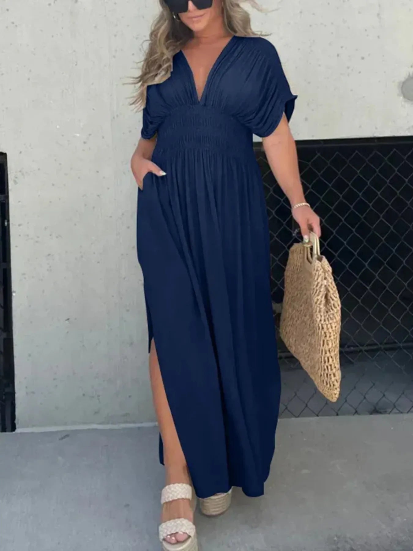 Woman wearing a flowing black deep V-neck maxi dress with side slit and relaxed elegant silhouette.