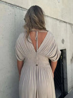 Woman wearing a flowing black deep V-neck maxi dress with side slit and relaxed elegant silhouette.