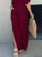 Woman wearing a flowing black deep V-neck maxi dress with side slit and relaxed elegant silhouette.