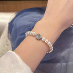 Sterling silver pearl bracelet featuring a blue gemstone centerpiece and elegant beaded design.